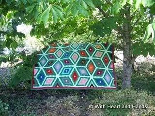 Detailed shot of hexagonal quilt blocks with a bright floral pattern laid out in a sunny outdoor setting, capturing vibrant colors and geometric design.